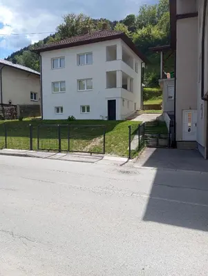 a white house with a fence next to a street at Apartmani Mušinbegović1 in Visoko