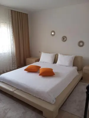 a bedroom with a large white bed with two orange pillows at Apartmani Mušinbegović1 in Visoko