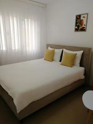 a large bed with white sheets and yellow pillows at Apartmani Mušinbegović1 in Visoko