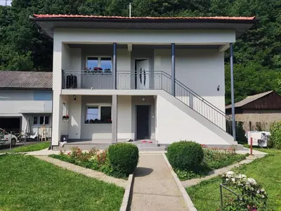 a white house with a balcony and a yard at Apartman Mir in Visoko