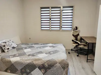a bedroom with a bed and a desk and a window at Apartman Mir in Visoko