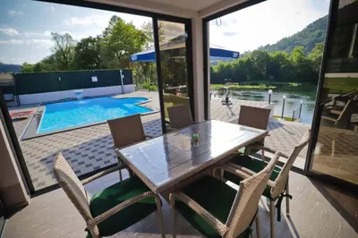 a dining room with a table and chairs and a pool at Villa Lux in Bosanska Krupa