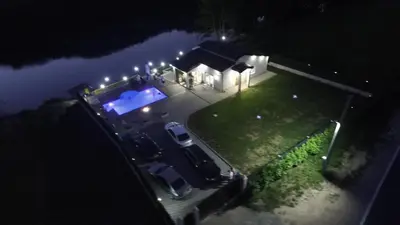 a couple of cars parked next to a swimming pool at night at Villa Lux in Bosanska Krupa