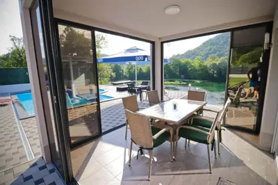 a dining room with a table and chairs on a patio at Villa Lux in Bosanska Krupa