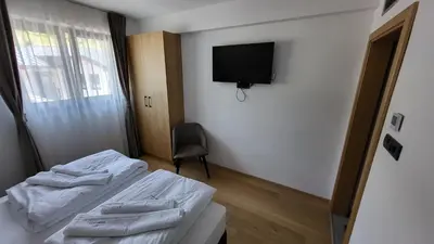 a bedroom with two beds and a tv on the wall at Janjska Kuća in Šipovo