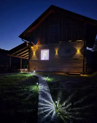 a cabin with lights on the side of it at night at Un Rio Sana in Gornji Ribnik