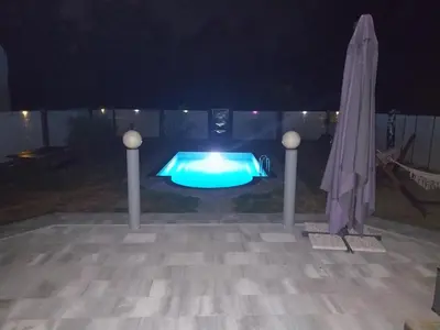 a swimming pool at night with an umbrella at Sarajevo Villa Sunce in Ilijaš