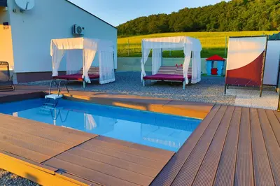 a swimming pool with two chairs next to a tent and aophe at Villa Bubinka in Bihać