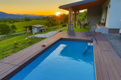 a swimming pool with a wooden deck next to a house at Villa Bubinka in Bihać