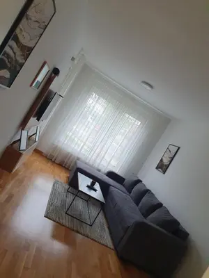 a living room with a black couch and a large window at Apartman Milekic in Banja Luka