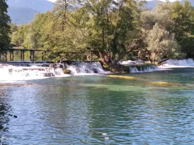 a waterfall in front of a river with trees at Apartman Leon in Bihać