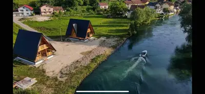a boat traveling down a river with two huts at Bungalow Jajce 1 in Jezero