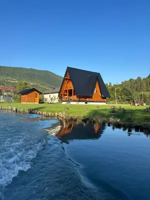 a large wooden cabin next to a body of water at Bungalow Jajce 1 in Jezero