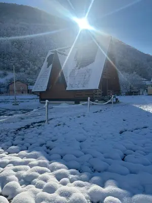 a building covered in snow with the sun behind it at Bungalow Jajce 1 in Jezero