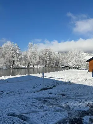 a snow covered field with a pond and trees at Bungalow Jajce 1 in Jezero