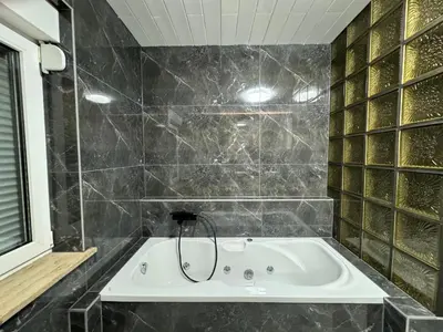a bathroom with a bath tub with black tiles at Lux apartments Crystal-center in Bihać