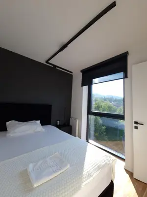 a bedroom with a white bed with a large window at Smart Loft Apartment - connection of city center and luxury in Tuzla
