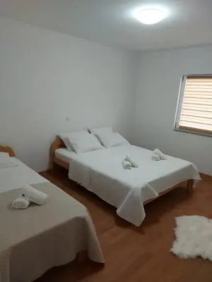 a white bedroom with two beds and a window at Apartmani Franciska in Jajce