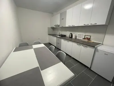 a kitchen with a long table and white cabinets at Apartmani Franciska in Jajce
