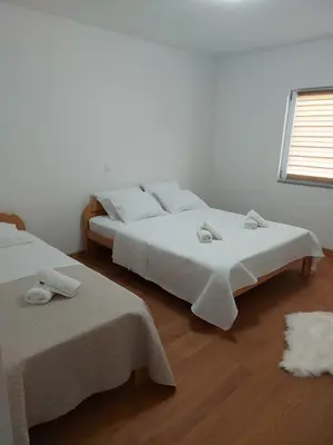 a bedroom with two beds with white sheets and a window at Apartmani Franciska in Jajce