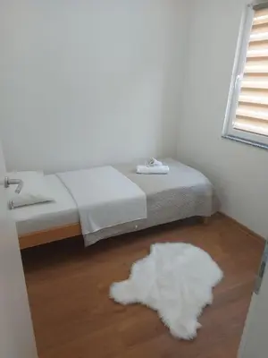 a bedroom with a bed and a white rug on the floor at Apartmani Franciska in Jajce