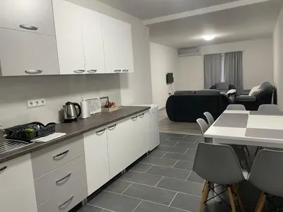 a kitchen with white cabinets and a living room at Apartmani Franciska in Jajce