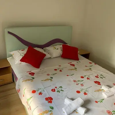 a bed with red pillows and a white comforter at Apartman TESA in Sanski most