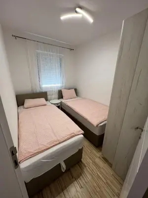 two beds in a small room with a window at Apartman Afrodita in Bosanska Gradiška