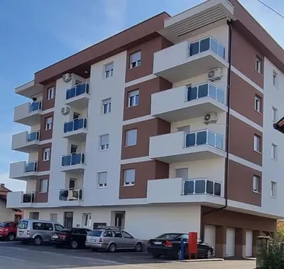 a large apartment building with cars parked in front of it at Stan na dan Tamaris in Modriča