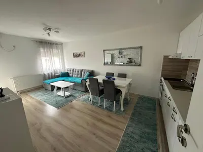 a kitchen and living room with a table and a couch at Stan na dan Tamaris in Modriča