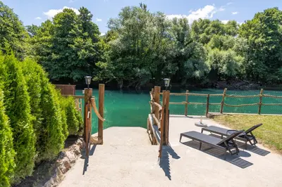 a bench sitting on a sidewalk next to a body of water at Villa UNA LUX in Bihać