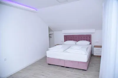a bedroom with a pink bed with white sheets and pillows at Vb apartmani in Prijedor