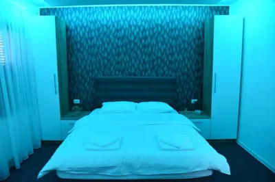a bedroom with a large white bed with blue lights at Vb apartmani in Prijedor