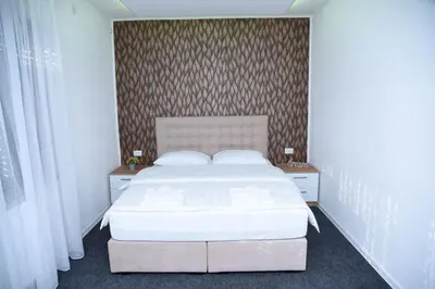 a bedroom with a white bed and two night stands at Vb apartmani in Prijedor
