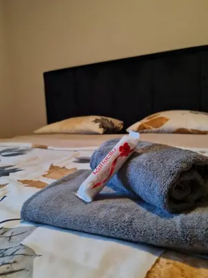 a pile of towels on a bed with a bottle ofodorant at AGERA Apartments in Banja Luka