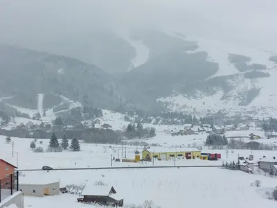 a snow covered village with a mountain in the background at Apartment Una in Kupres