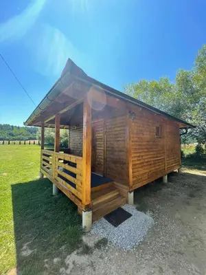 a large woodenshed with a roof on a field at Etno zona Oaza mira in Donji Vakuf