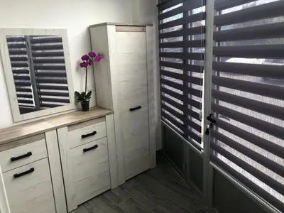 a bathroom with white cabinets and a window with blinds at Apartman 555 in Travnik