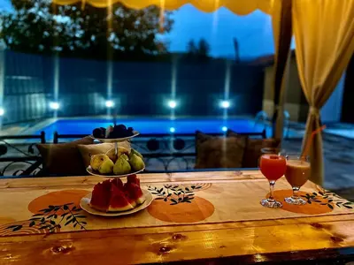 a table with a plate of fruit and two glasses of juice at Summer house LejHana in Bihać
