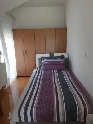 a bedroom with a large bed with a striped blanket at Stan na dan Modriča in Modriča
