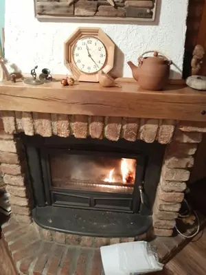 a fireplace with a clock on top of it at Vikendica Volar in Prijedor
