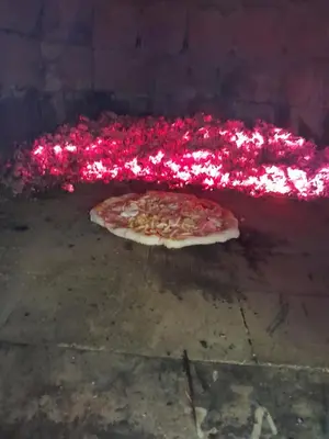 a pizza is cooking in a brick oven at Vikendica Volar in Prijedor