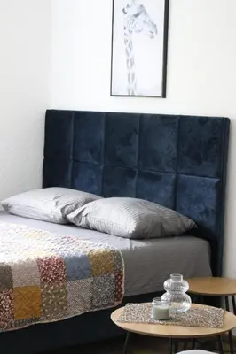 a bed with a blue headboard next to a table at Blue Apartment in Bihać