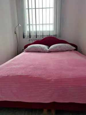 a pink bed with two pillows in a bedroom at Apartman Kumalic in Sanski most