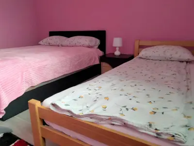 a bedroom with two beds and a pink wall at Apartman Kumalic in Sanski most