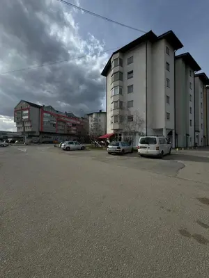 a parking lot with cars parked in front of a building at Apartman Kumalic in Sanski most