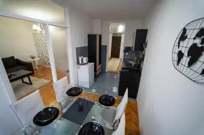 a living room with a glass table and a kitchen at Park Apartment in Visoko
