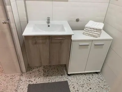 a bathroom with a white sink and a shower at Apartman UNA-Plandište in Bihać