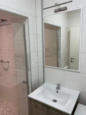 a bathroom with a sink and a shower with a mirror at Apartman UNA-Plandište in Bihać
