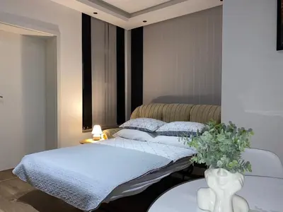 a bedroom with two beds and a vase with flowers on a table at Apartman UNA-Plandište in Bihać